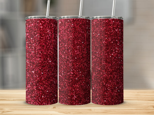 Three glittery red tumblers with white straws on a wooden surface.