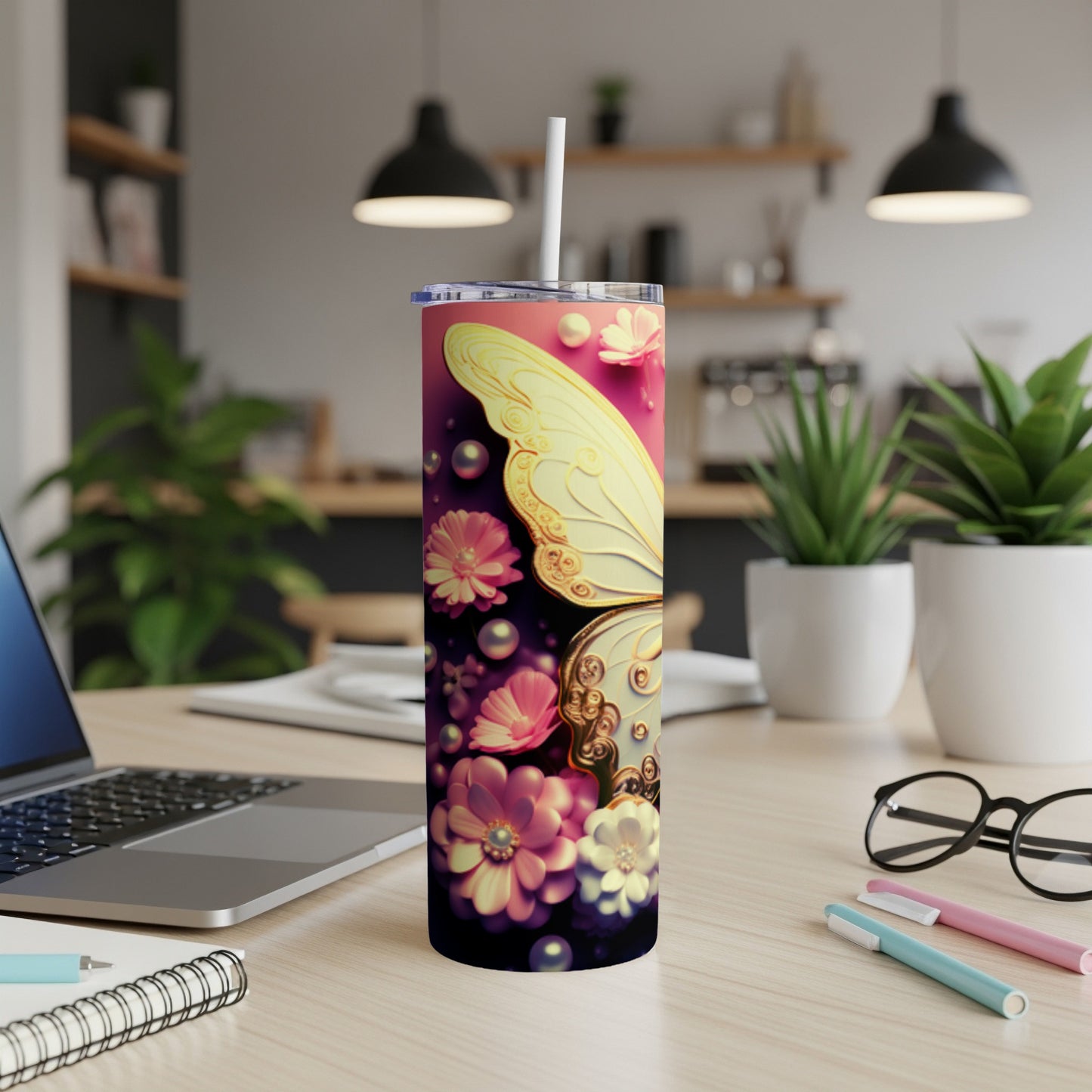 Tumbler with a butterfly and floral design, on a desk.