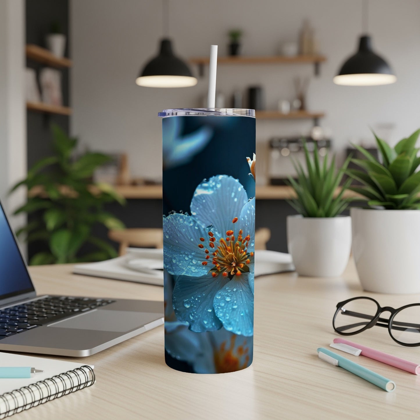 Blue flower with water droplets on a stainless steel tumbler with a straw.