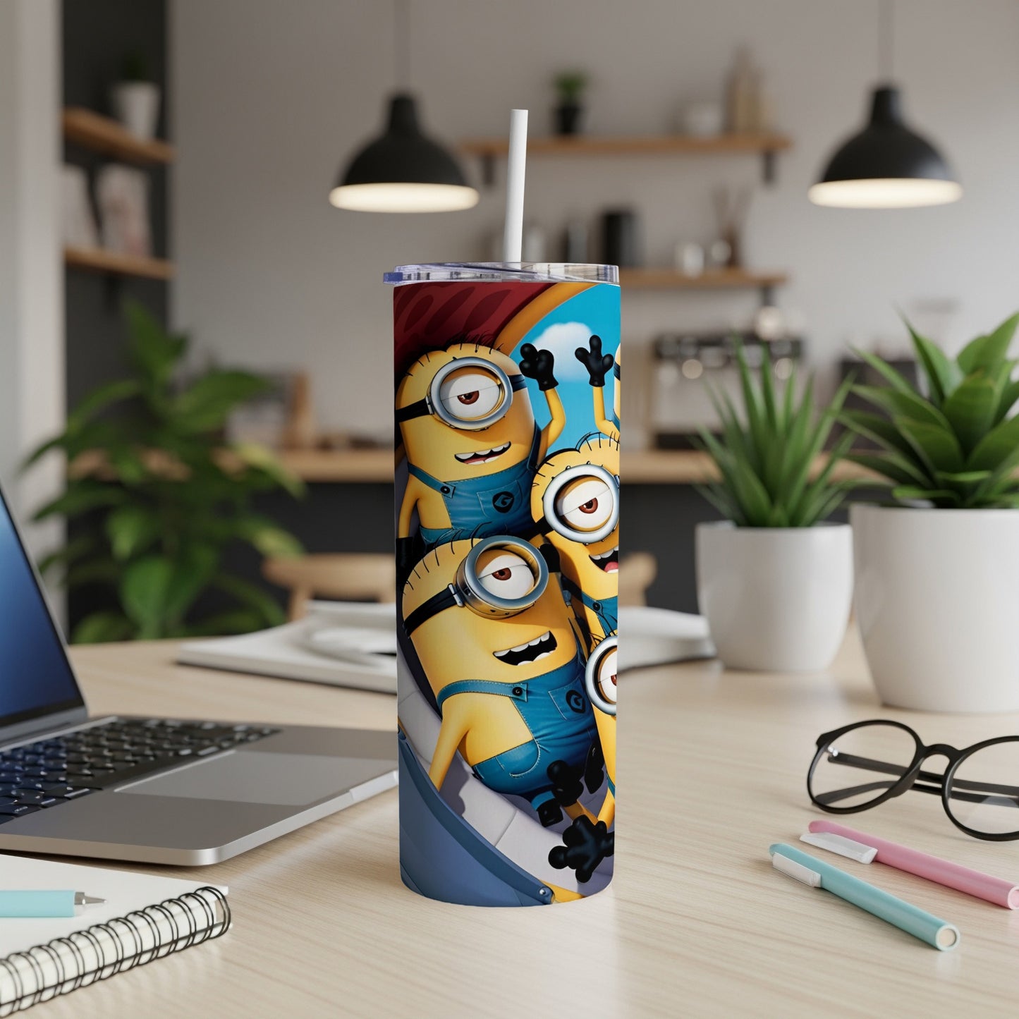 Minions cartoon characters on a blue tumbler with a straw on a desk.