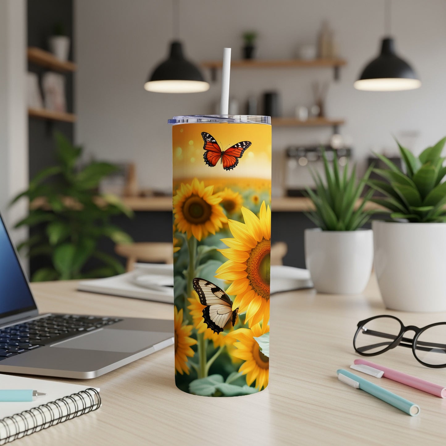 Sunflower and butterfly print skinny tumbler with straw on desk.