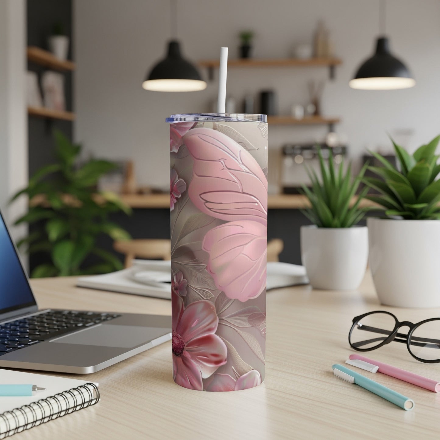 Floral patterned tumbler with butterfly design and straw on desk.