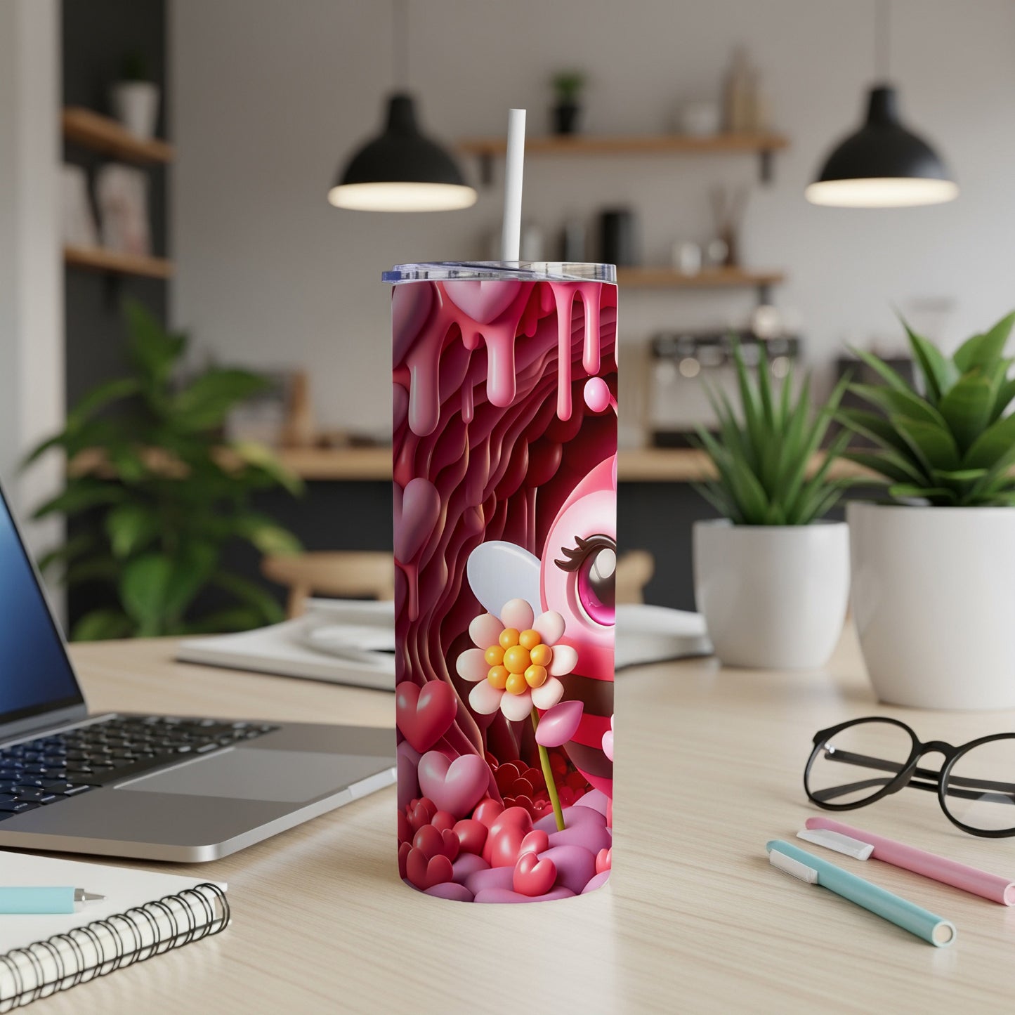 Pink, heart-covered tumbler with a cartoon bee design, on a desk.