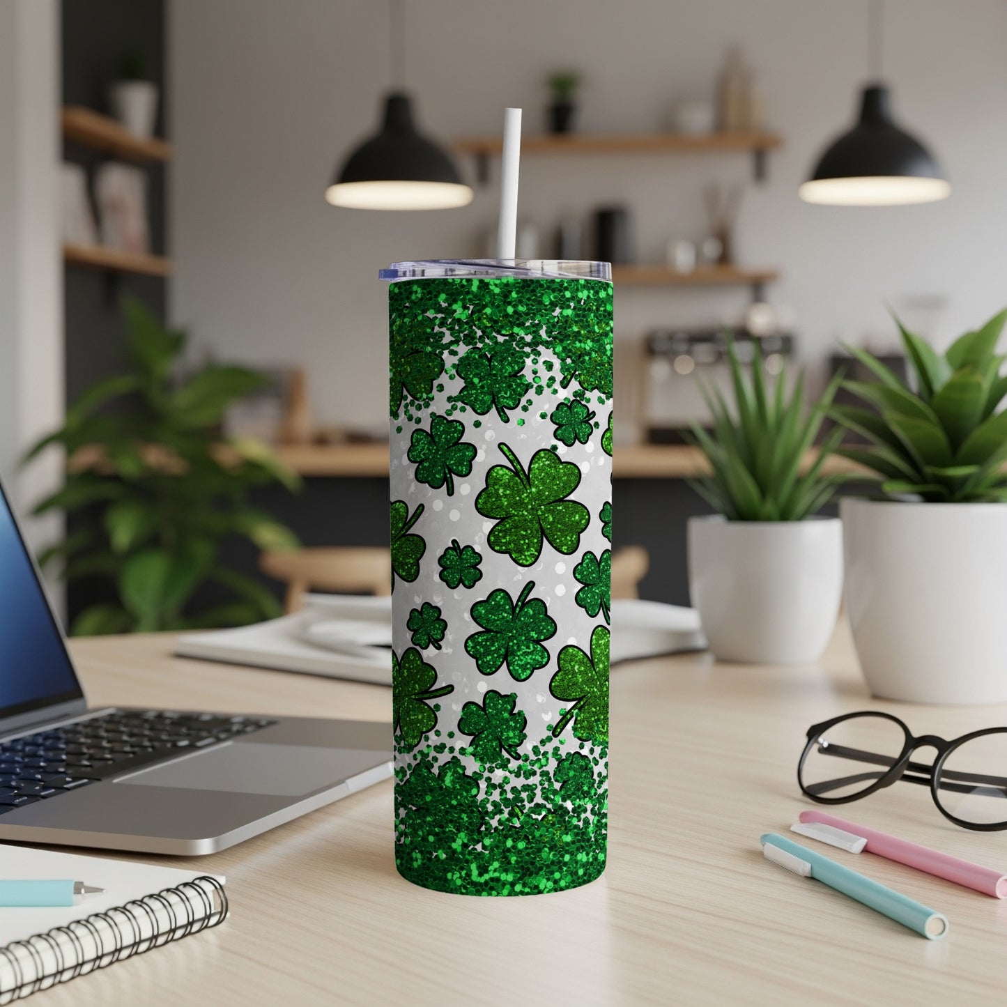 Green glitter shamrock tumbler with white lid and straw on desk.