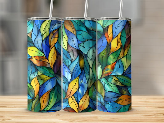 Three stained glass tumblers with colorful leaf patterns on a wooden surface.