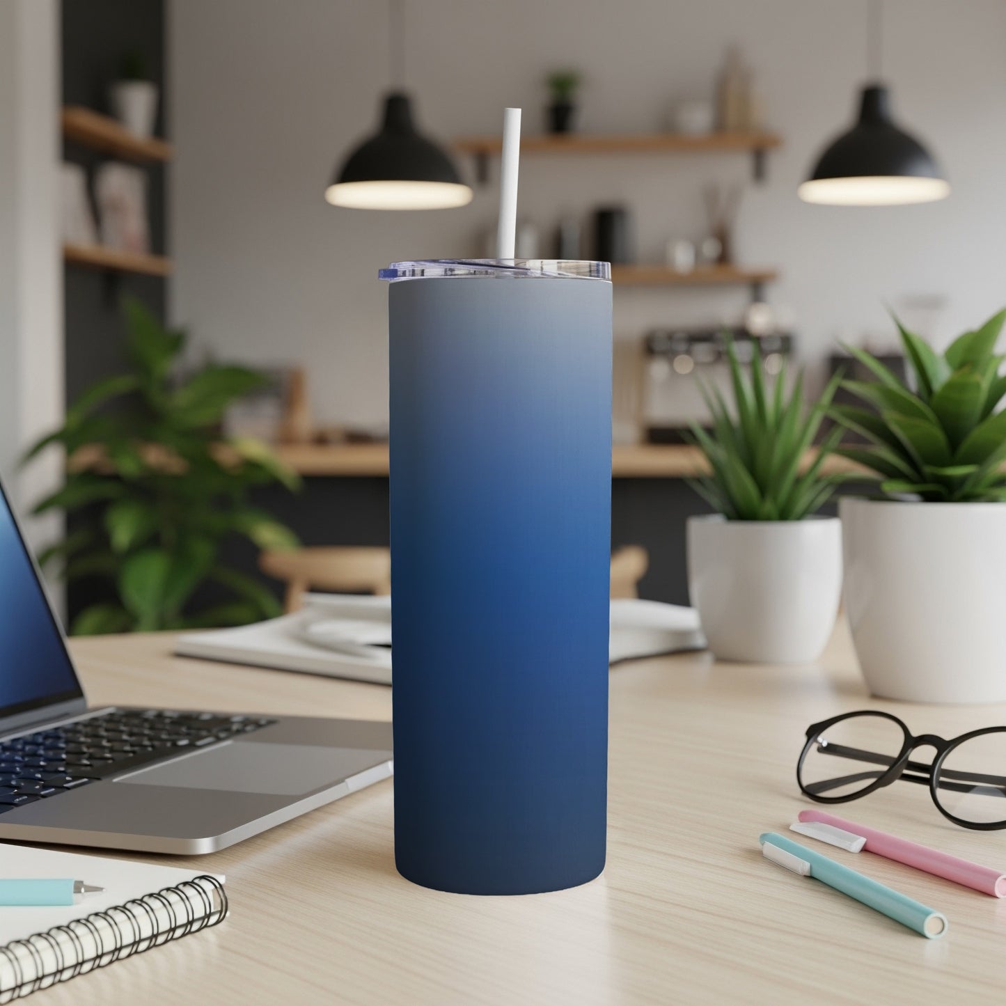Blue gradient tumbler with straw on a desk with a laptop.