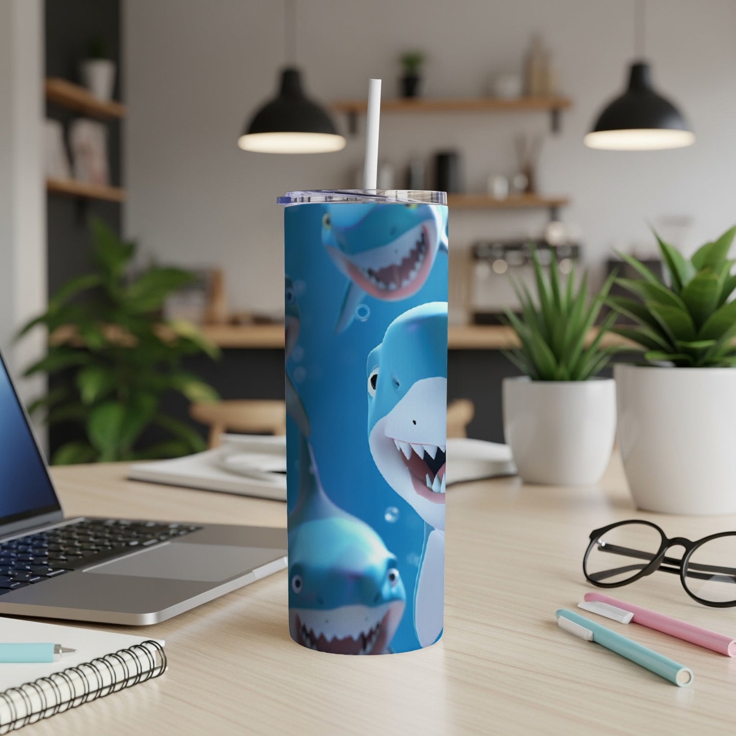 Blue tumbler with cartoon sharks and smiling faces, straw inserted.