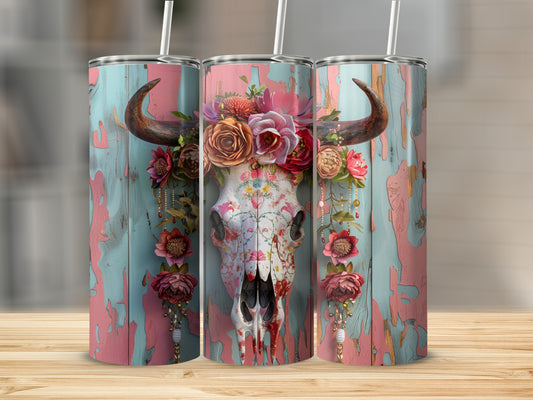 Floral embellished bull skull on a distressed teal and pink wooden background.