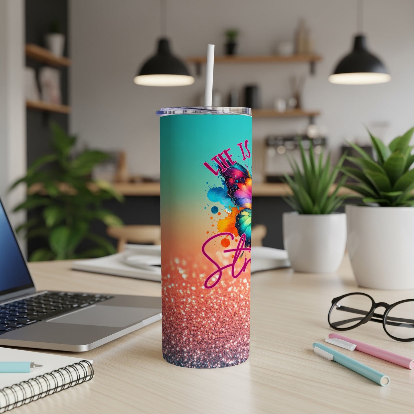Teal tumbler with "Life is Stronger" text and glitter design.
