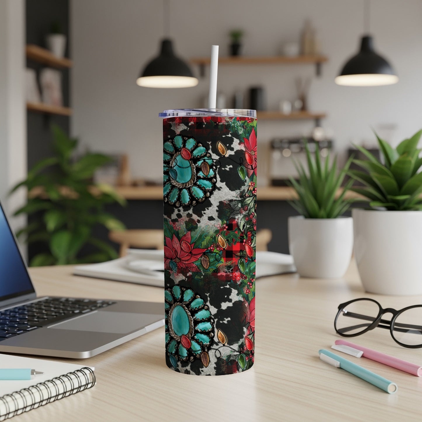 Turquoise, red, and black patterned tumbler with straw on a desk.