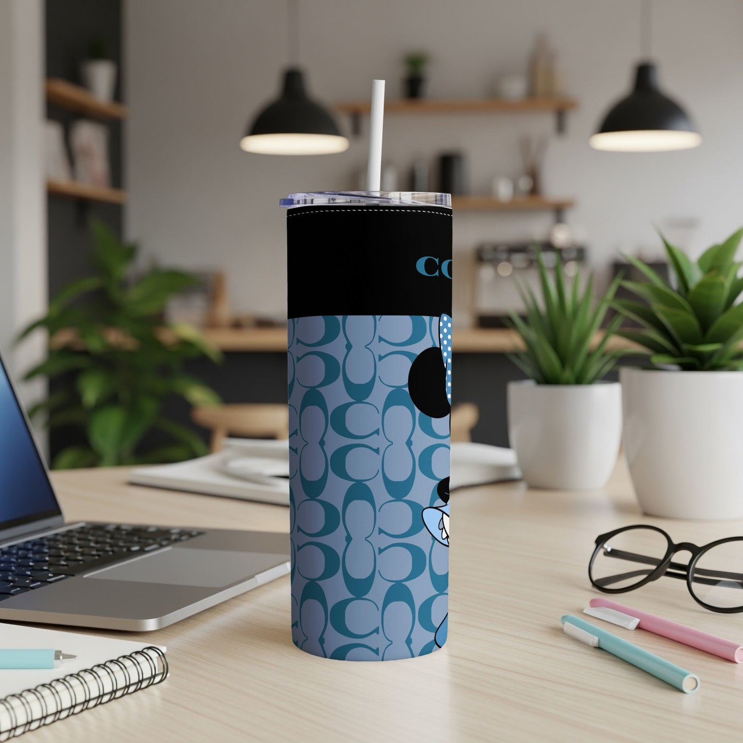 Coach x Minnie Mouse tumbler with straw on a desk.
