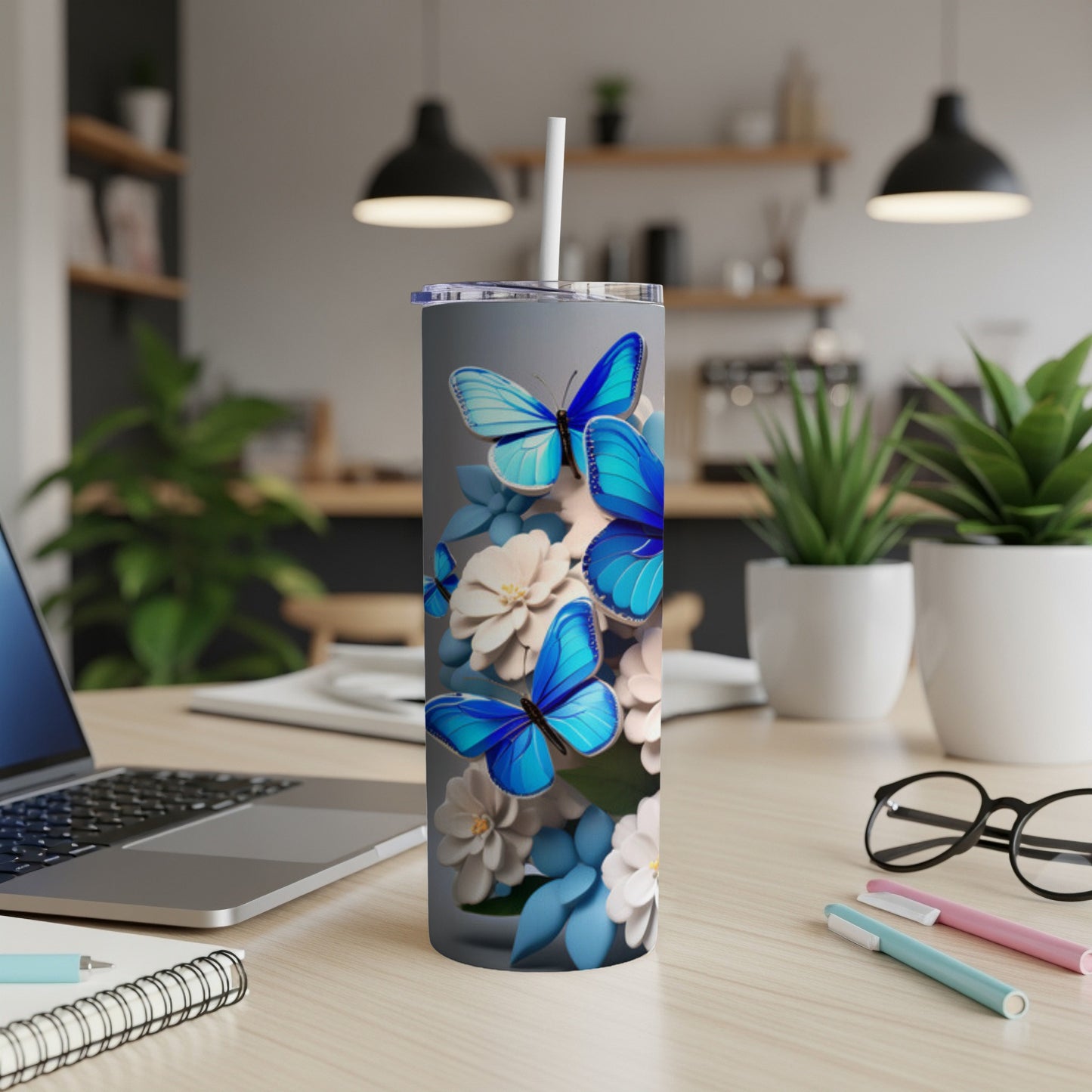 Blue butterflies and white flowers on a gray tumbler with a straw.