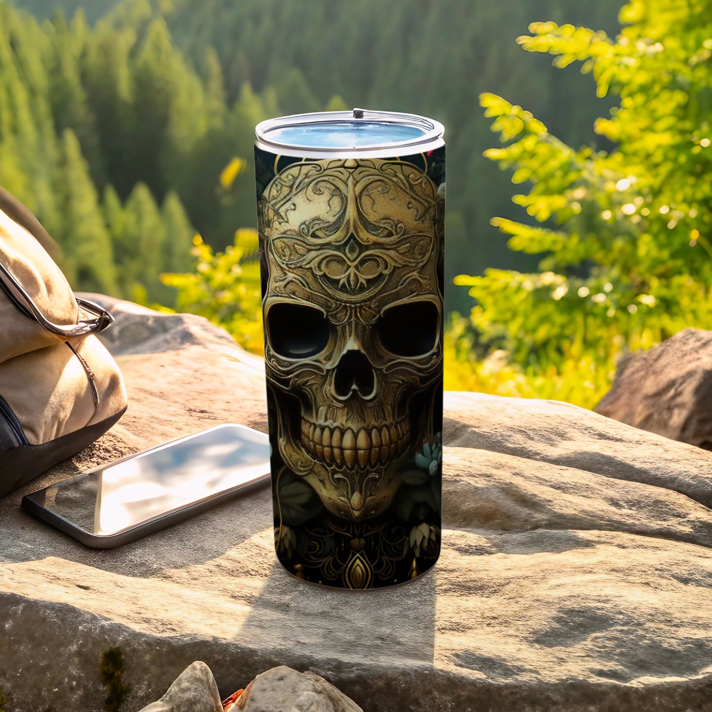 Ornate skull design on a stainless steel tumbler with phone and backpack.