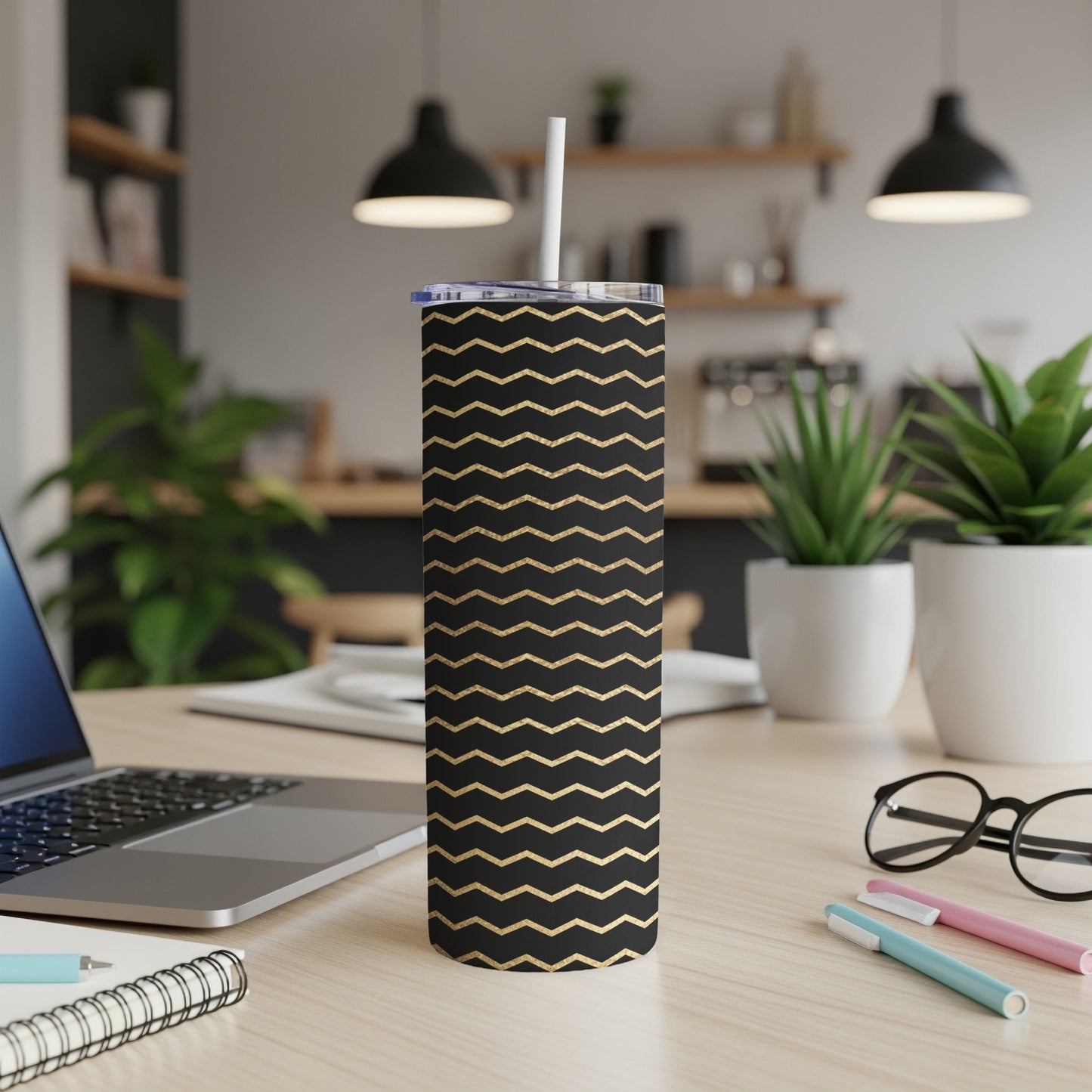 Black tumbler with gold zigzag pattern and white straw on a desk.