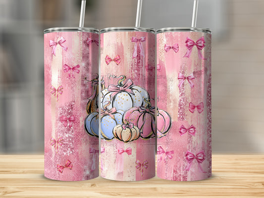 Pink, glittery tumblers with bows and pumpkins, arranged on a wooden surface.