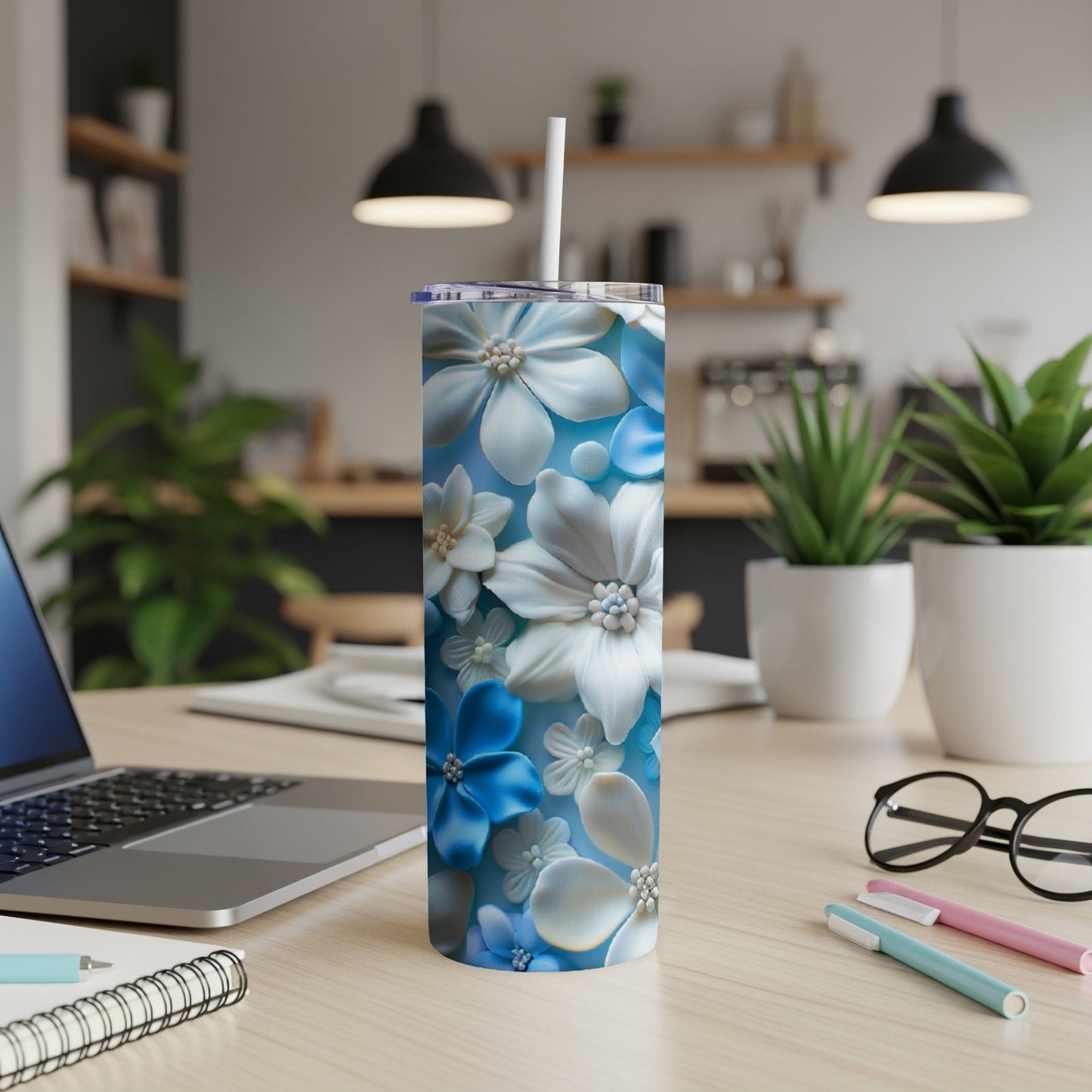 Blue and white floral skinny tumbler with straw on desk.