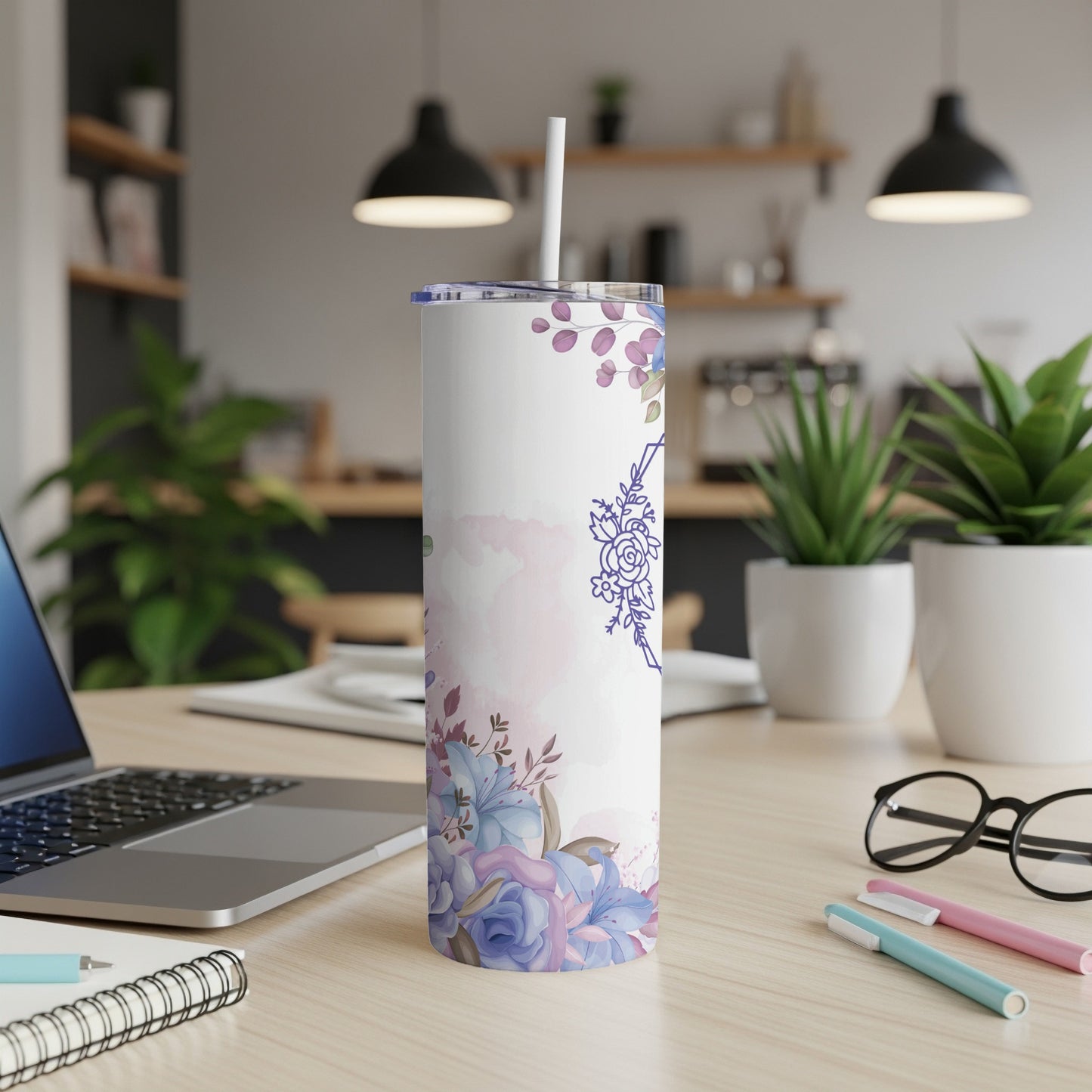 White tumbler with blue floral design and straw on a desk.