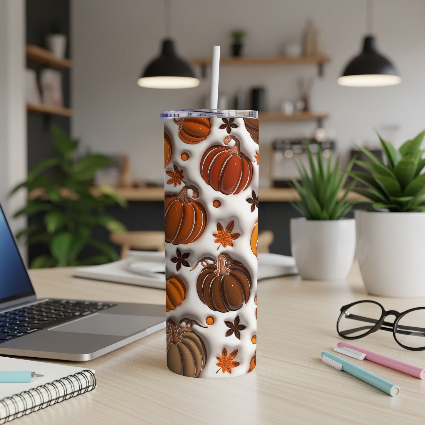 White tumbler with colorful pumpkin and leaf pattern on a desk.