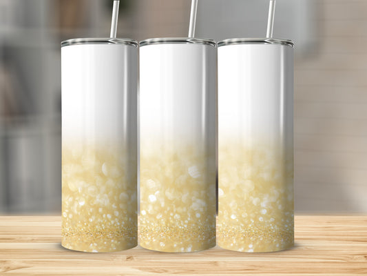 Three white tumblers with gold glitter ombre design and straws.