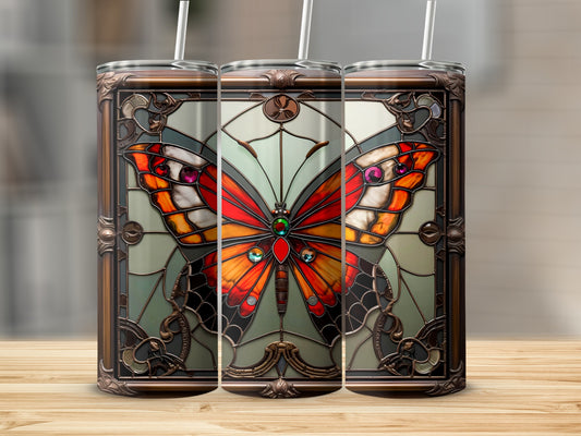 Stained glass butterfly tumbler with straw on wooden surface.