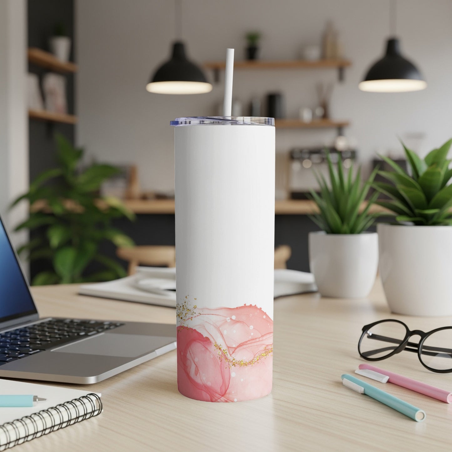White tumbler with pink and gold abstract design on desk with laptop.