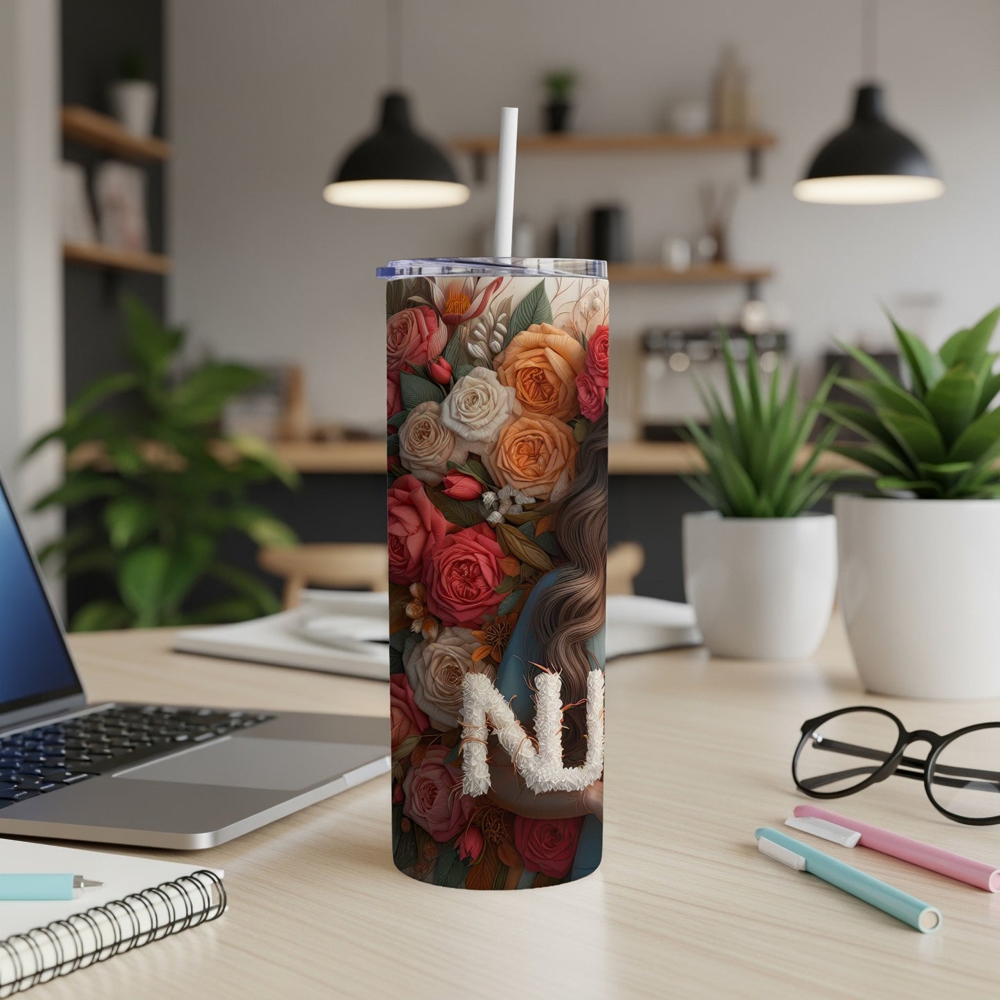 Floral tumbler with "Mom" written in flowers, on a desk.