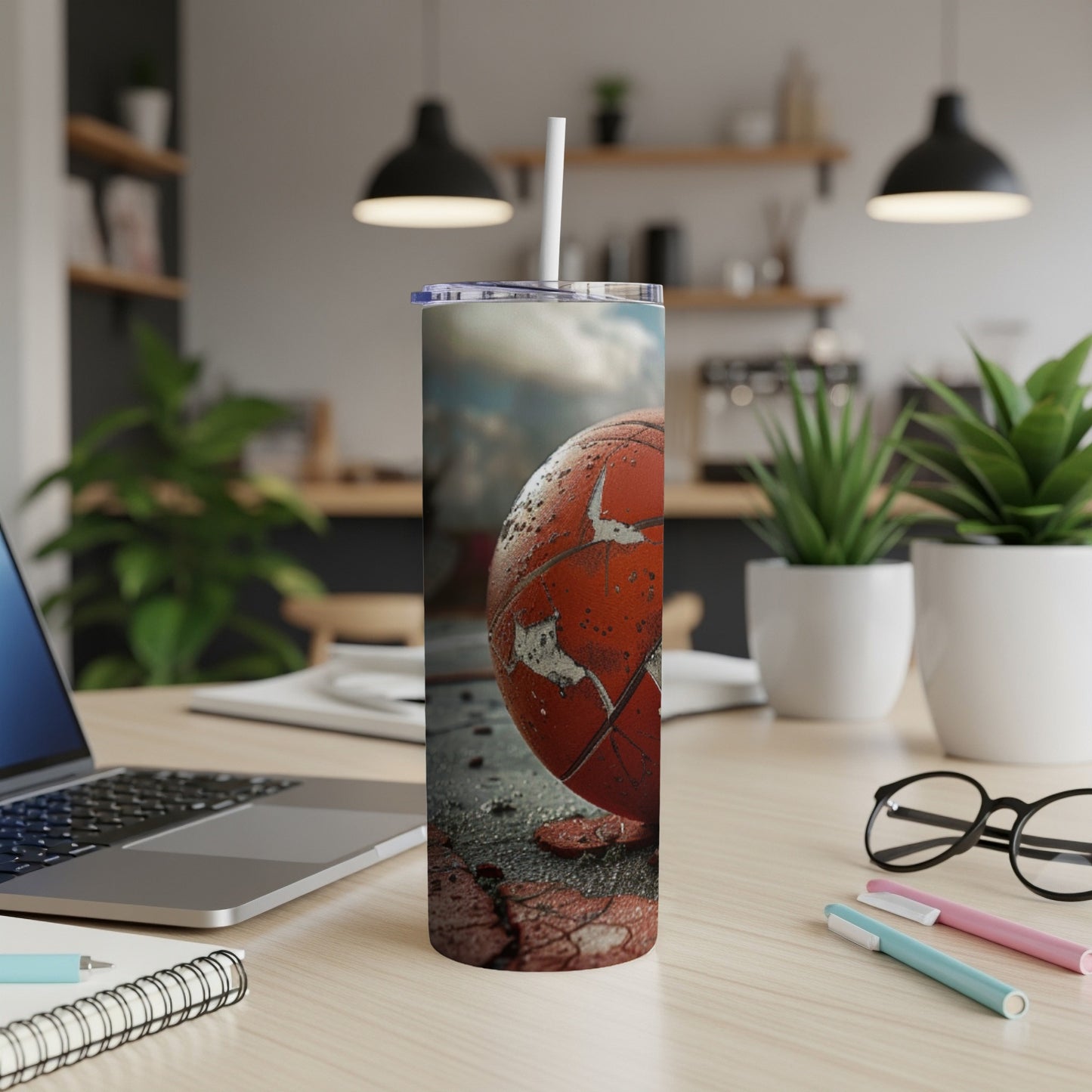 Orange basketball texture on a tumbler with straw on a desk.