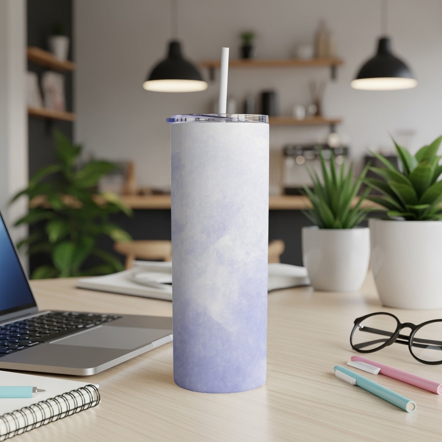 Purple and white tie-dye patterned tumbler with straw on a desk.
