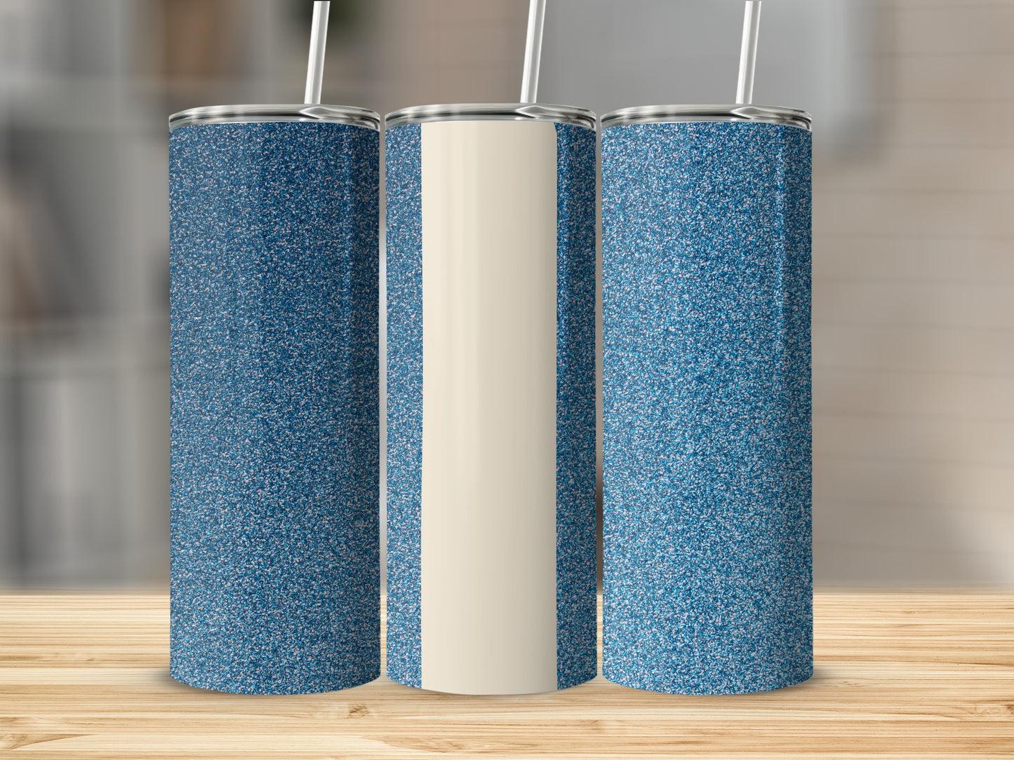 Three glitter-covered tumblers with straws on a wooden surface.