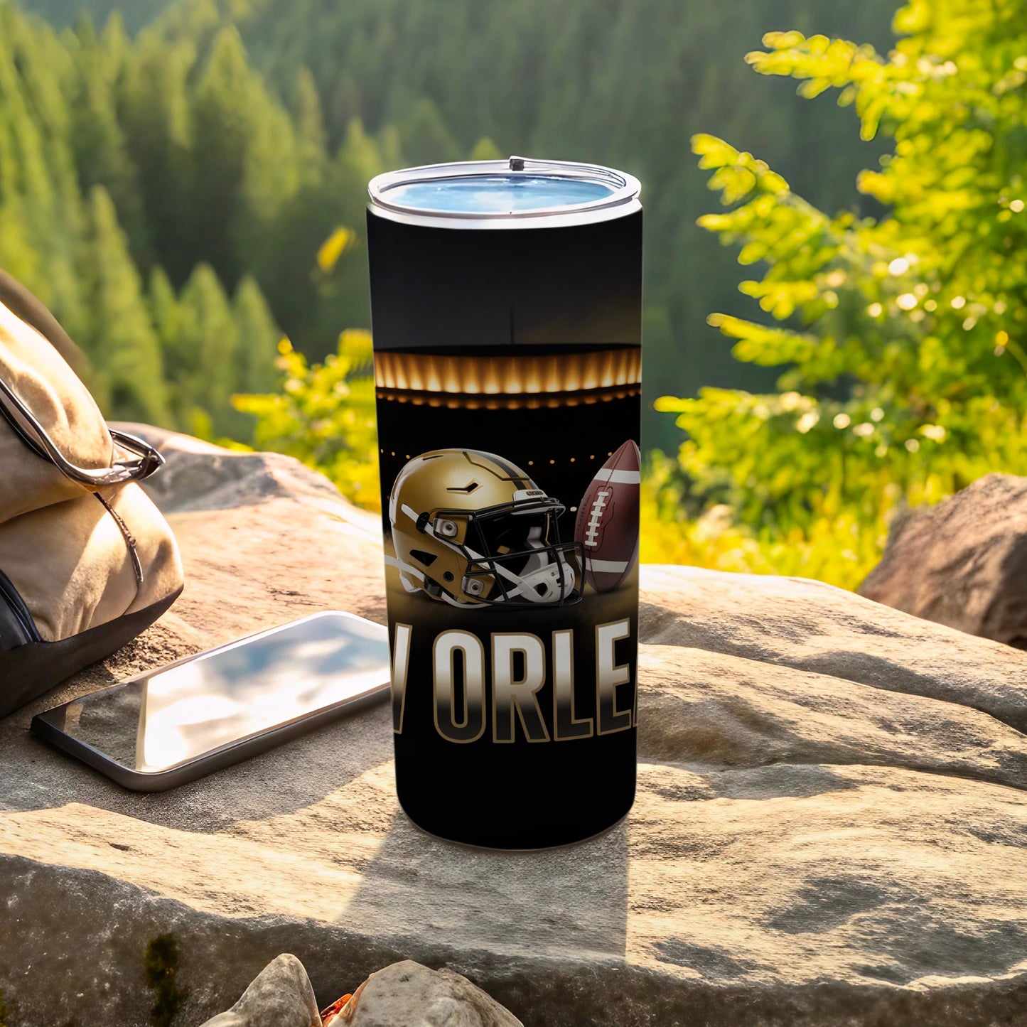 Black tumbler with football helmet and text "ORLE" on a rocky outdoor surface.