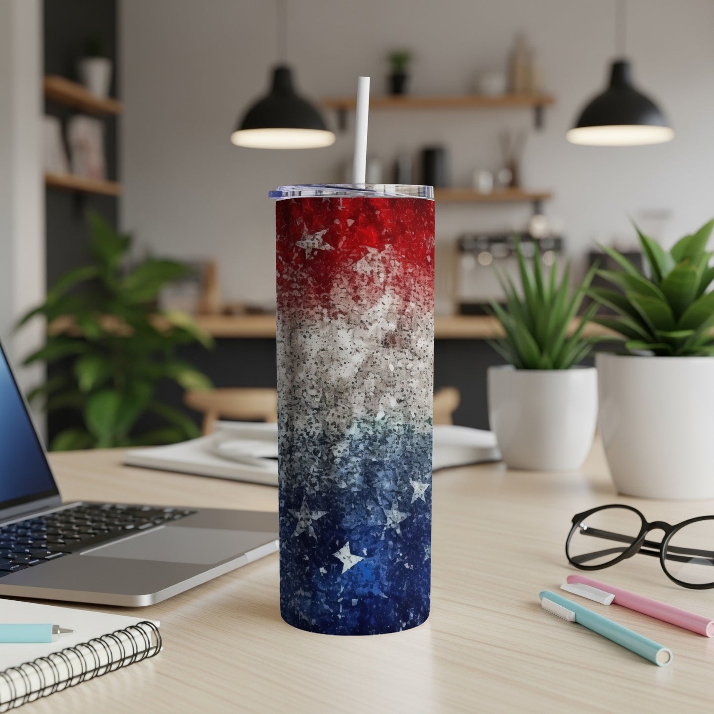 Red, white, and blue speckled tumbler with stars, on a desk.