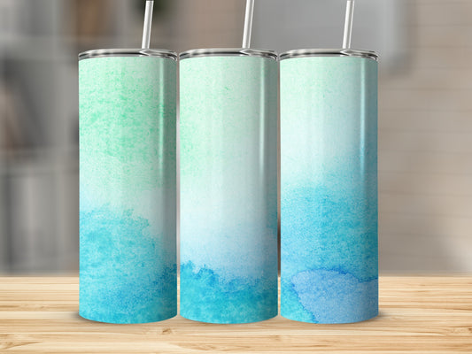 Three tumblers with blue and green watercolor designs stand on a wooden surface.
