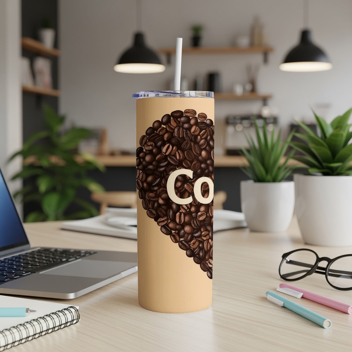 Tumbler with coffee beans and "Co." text on a desk.