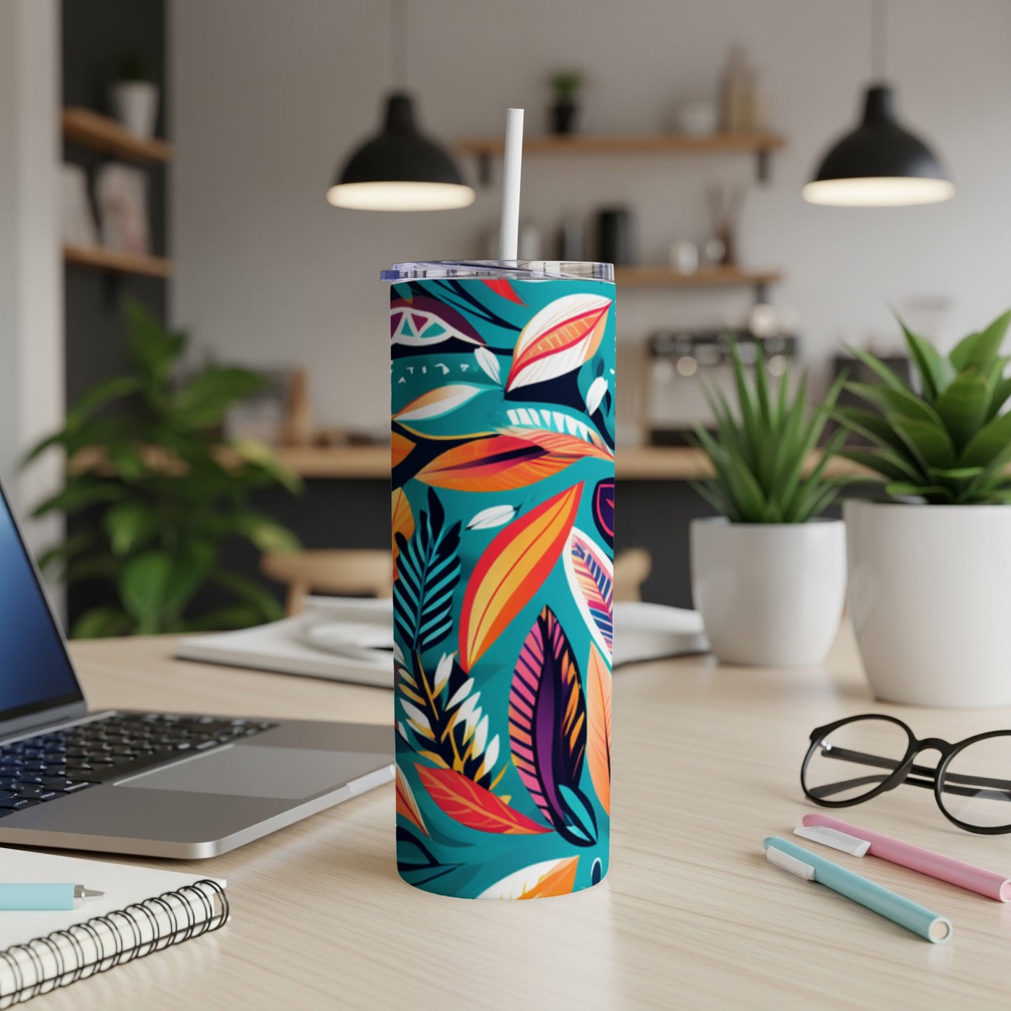 Teal tumbler with colorful tropical leaf pattern on desk.