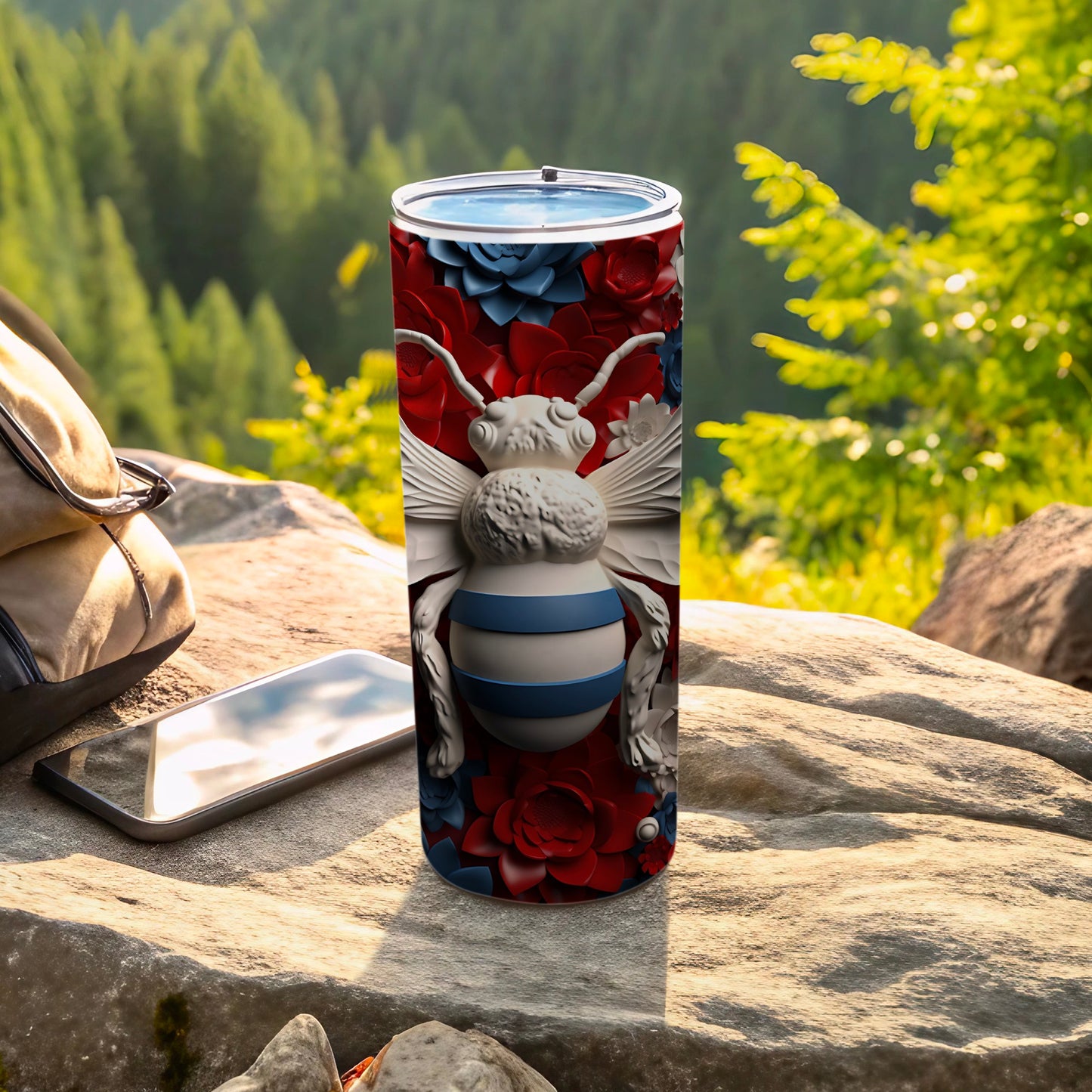 Bee and floral pattern on a stainless steel tumbler on a rock outdoors.