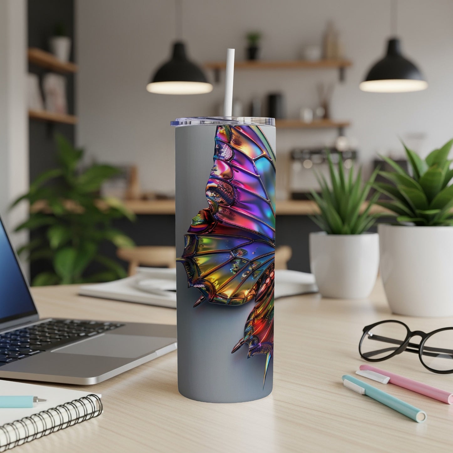 Iridescent butterfly wing on a silver tumbler with a straw.