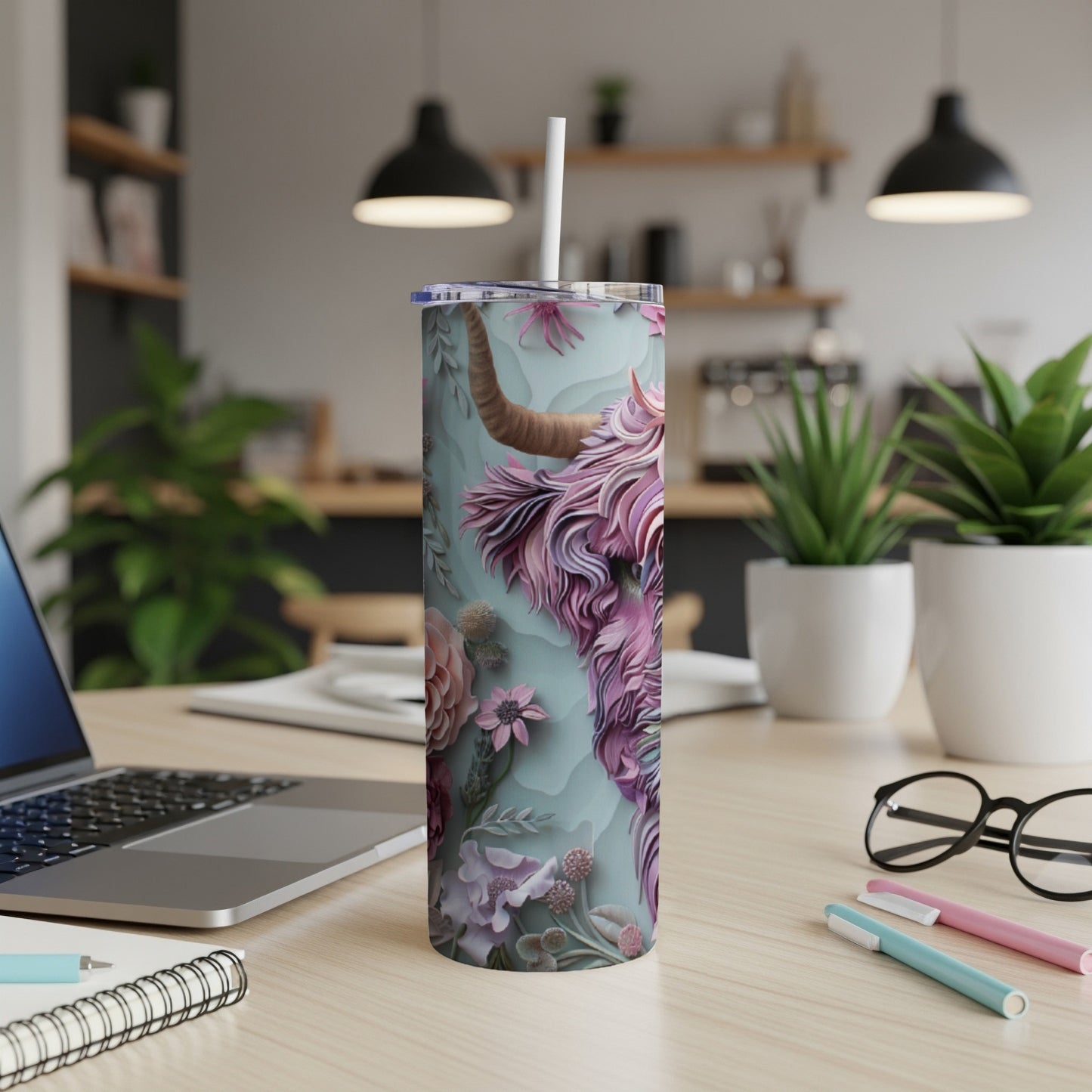 Floral Highland cow tumbler with straw on a desk.