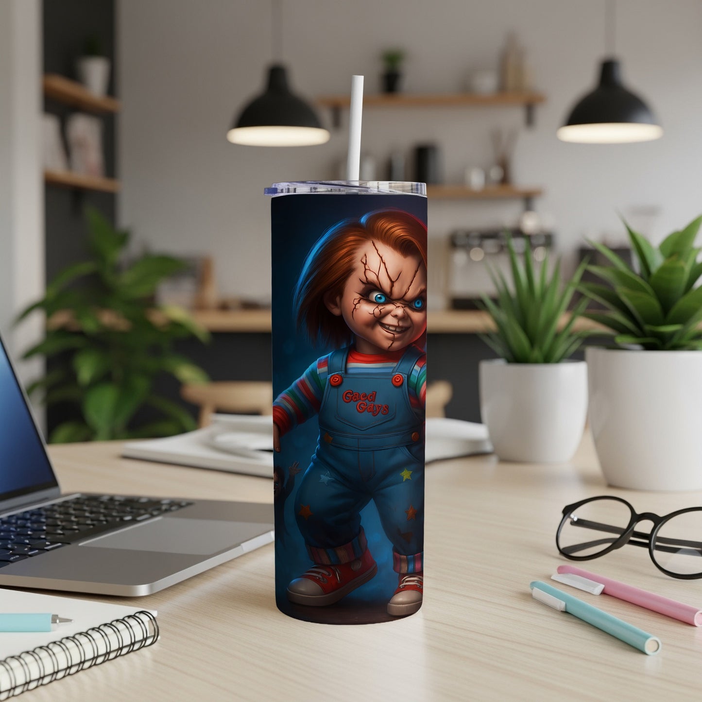 Tall tumbler with a Chucky doll design and a straw, on a desk.