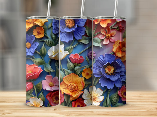 Three tumblers with raised colorful floral designs on a wooden surface.
