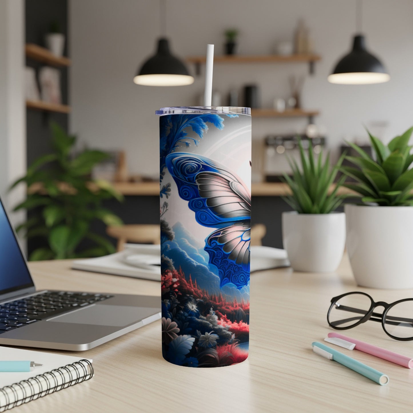 Tall tumbler with blue butterfly and floral designs on desk.