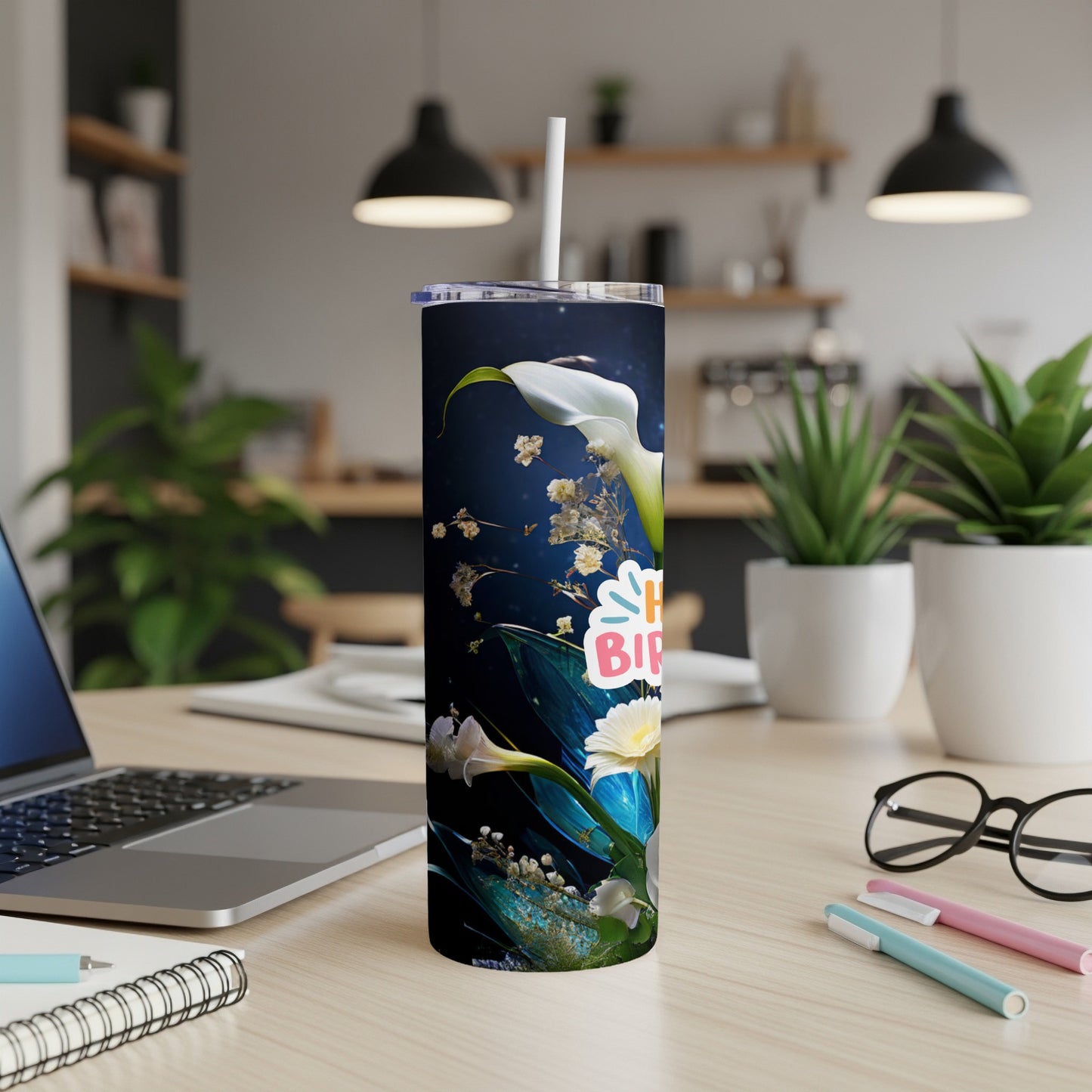 "Happy Birthday" tumbler with floral design on a desk with a laptop and pens.