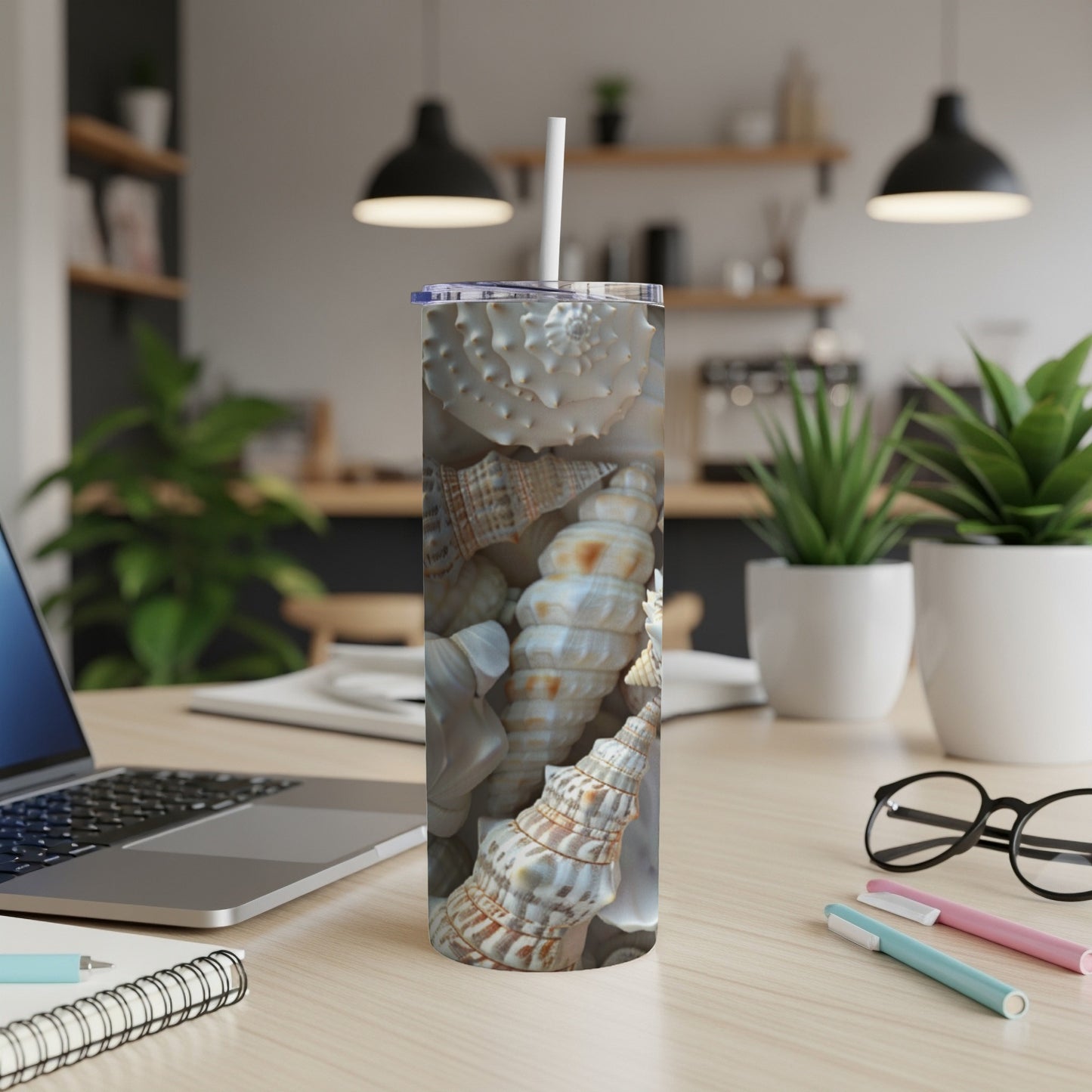 Tall tumbler with detailed seashell pattern on a wooden desk.