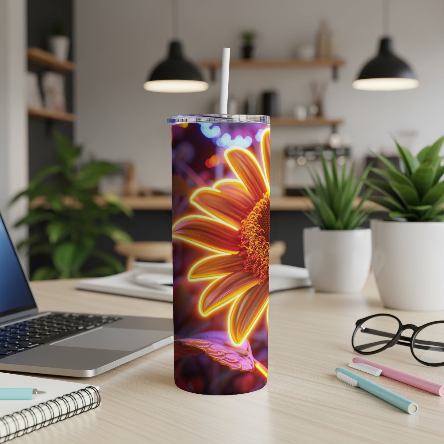 Tall tumbler with a glowing orange sunflower design on a desk.