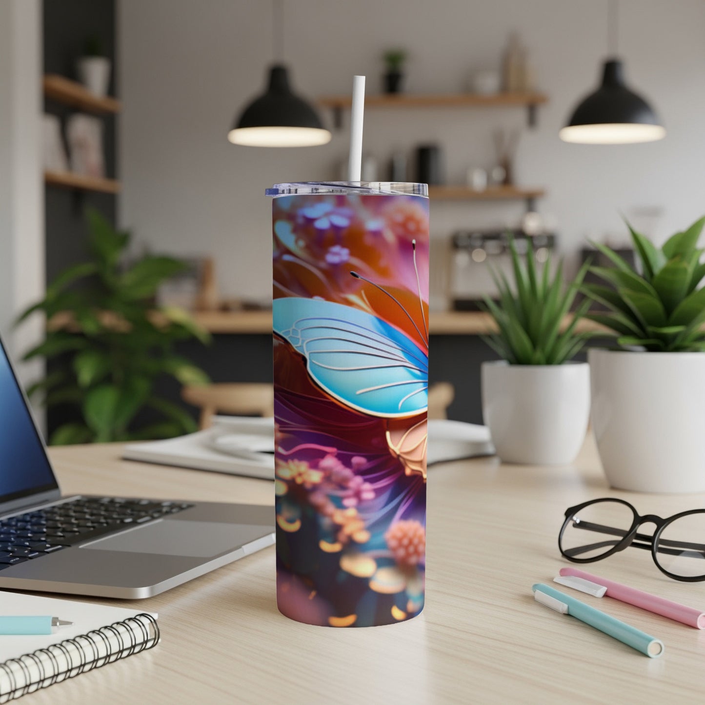 Colorful butterfly tumbler with straw on a desk with a laptop.