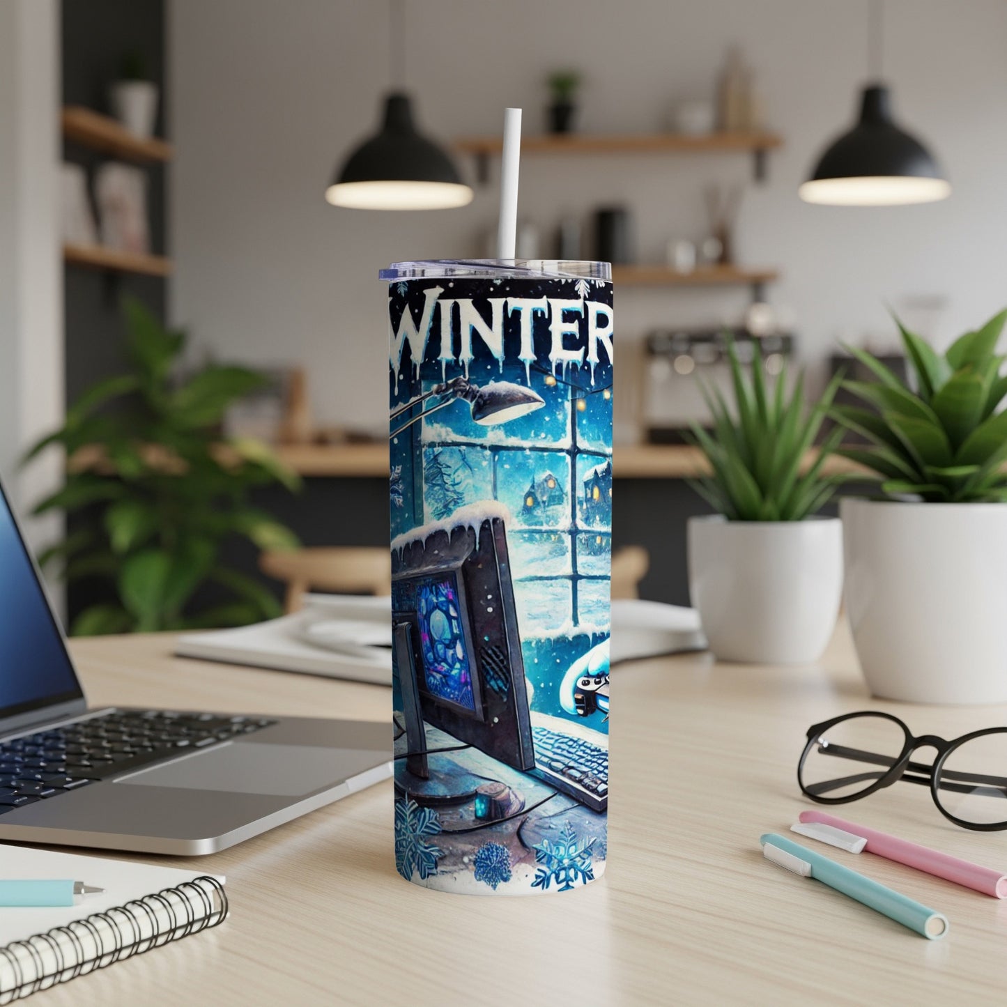 Winter-themed tumbler with computer and snowflakes on a desk.