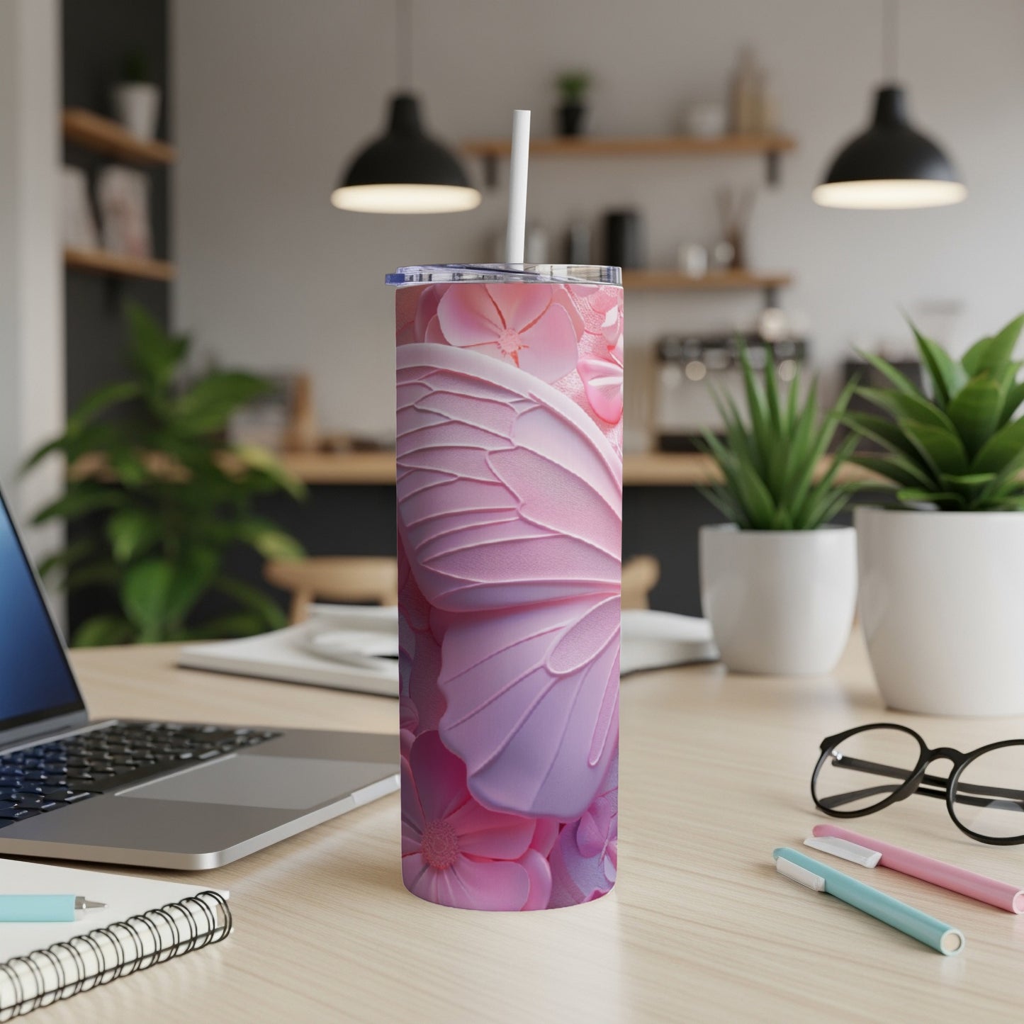 Pink butterfly wing tumbler with straw on desk.
