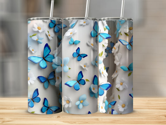 Three tumblers with blue butterflies and white flowers on a wooden surface.