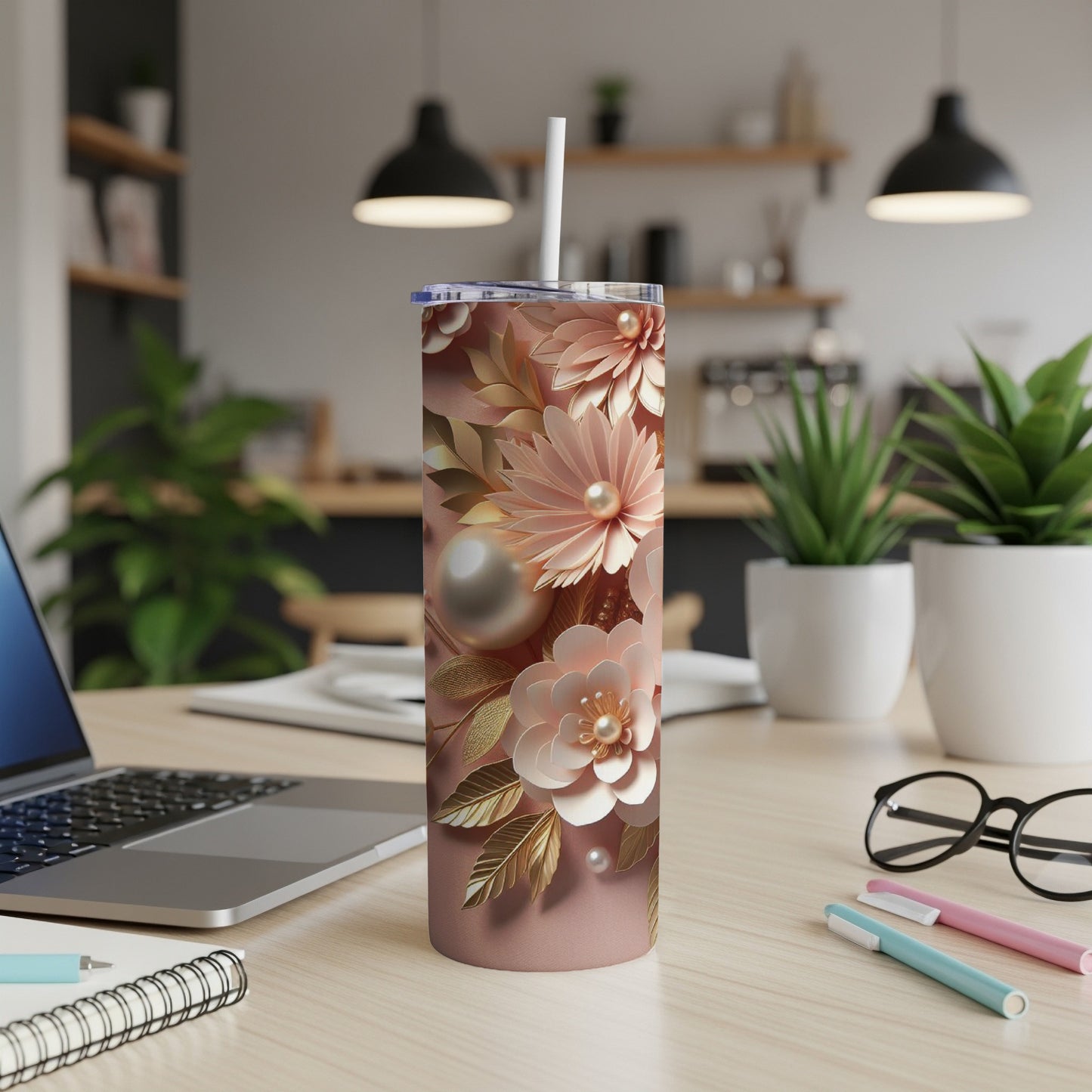 Rose gold floral pattern tumbler with pearls and straw on desk.