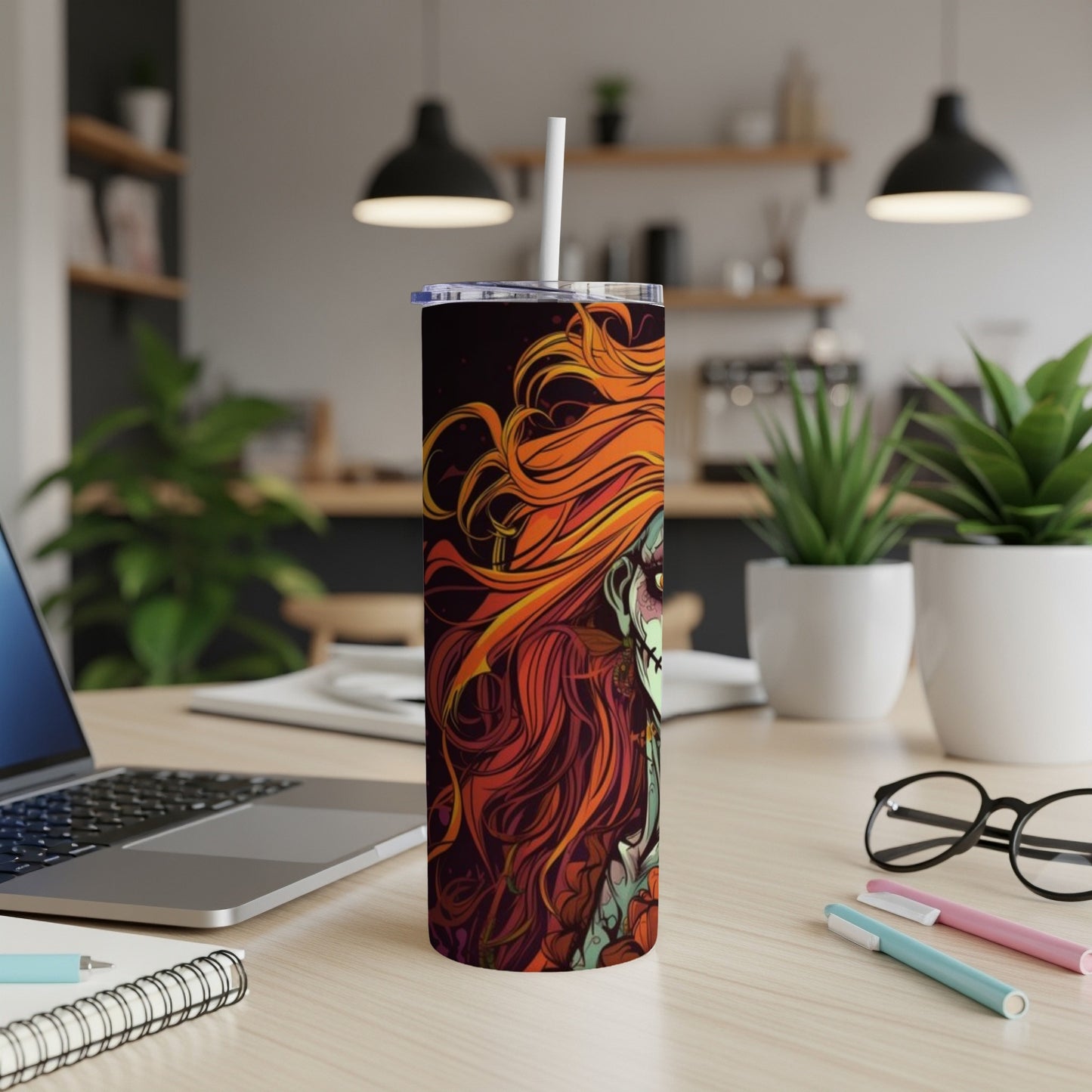Tumbler with fiery red hair and gothic face art, on a wooden desk.