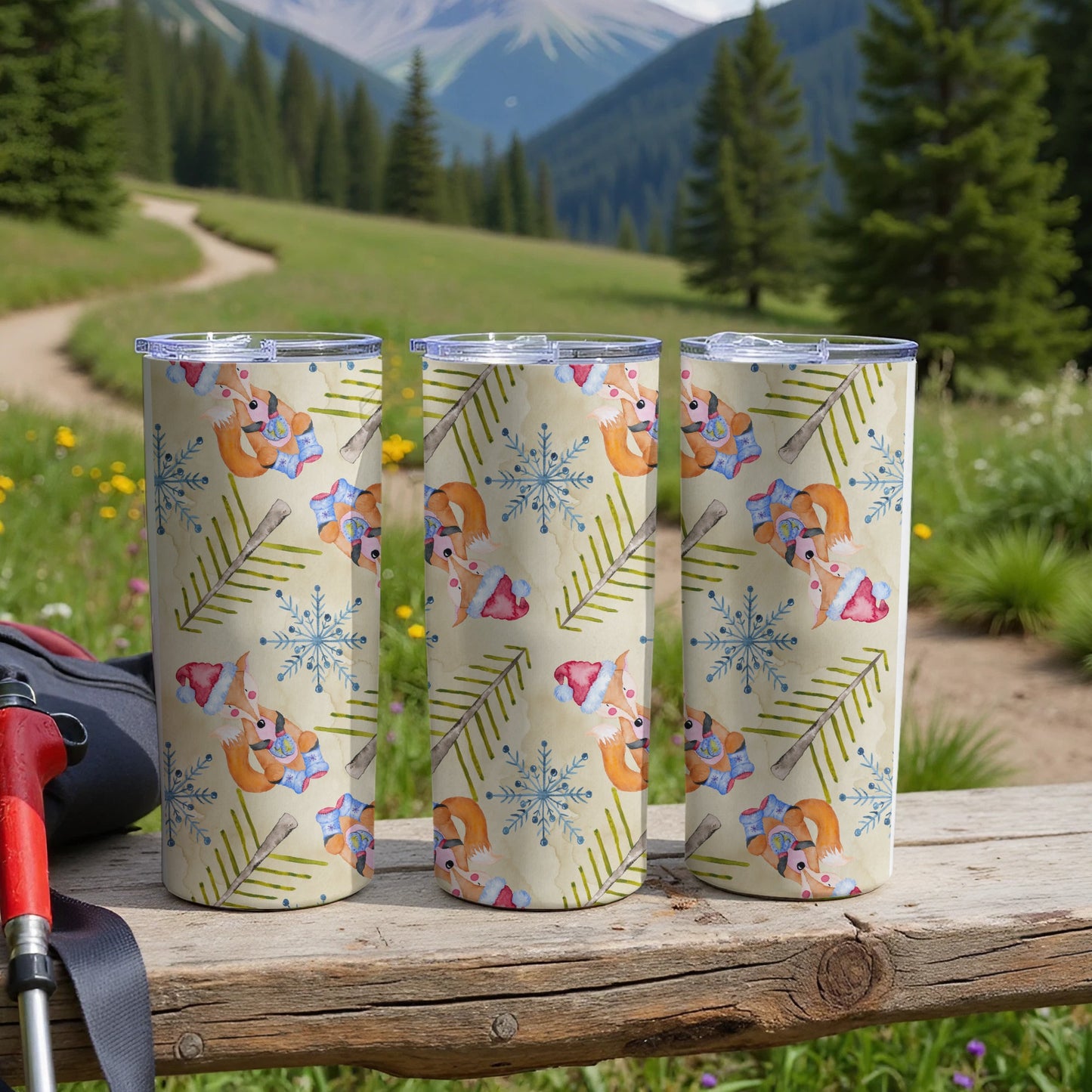 Three tumblers with fox, snowflake, and pine branch pattern on wooden surface.
